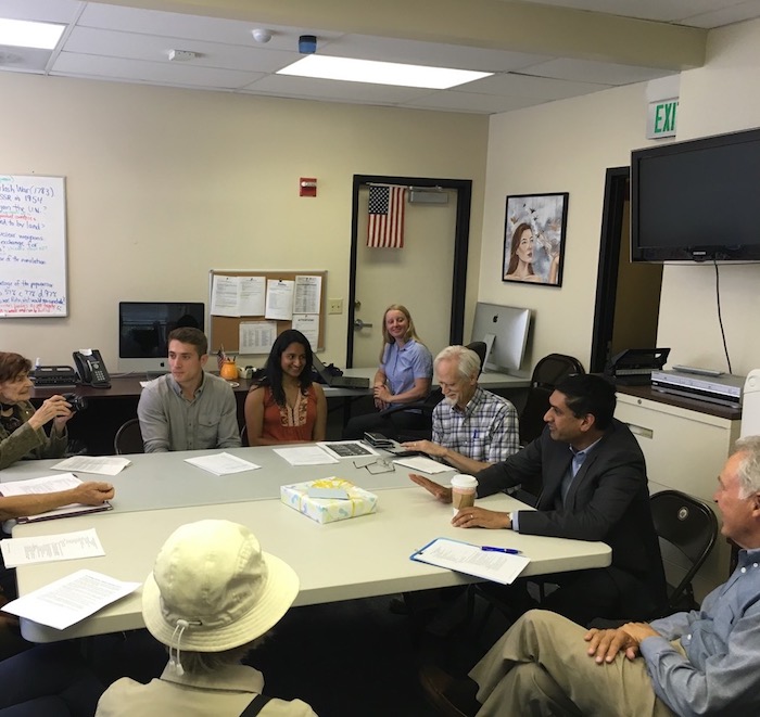 Photo of a dozen people seated around a table in a meeting room, including Representative Ro Khanna